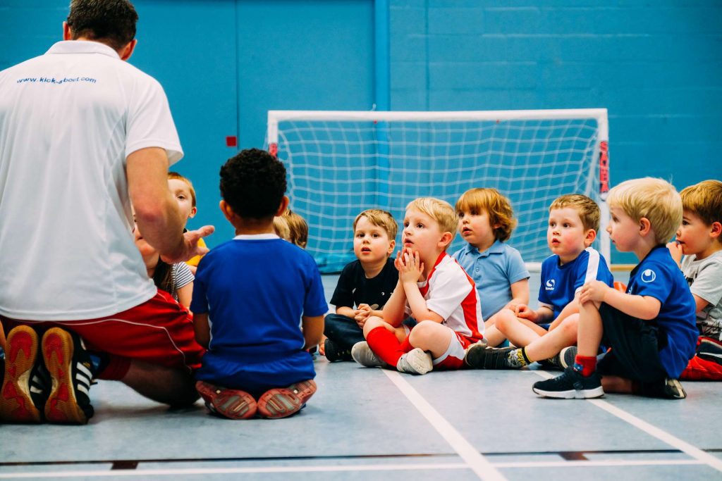 Coach helping children during a Kick-A-Bout activity